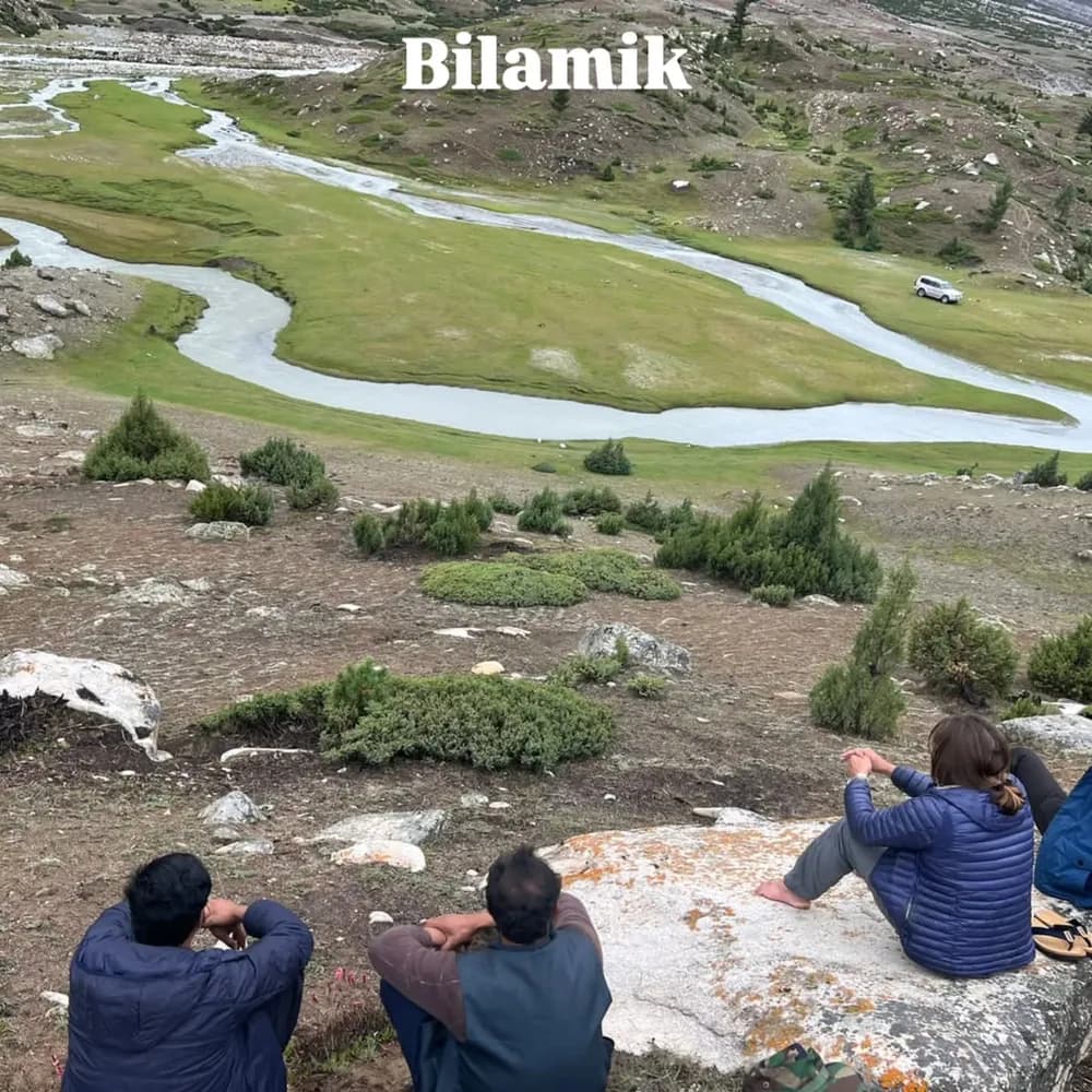 Two trekkers looking out over the green Bilamik valley